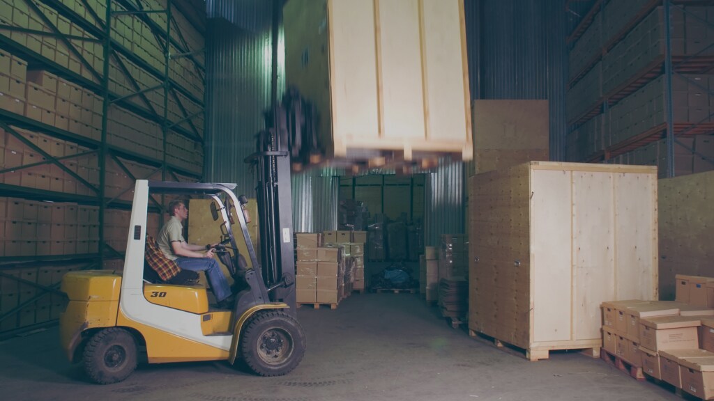 Male arranging the shipments using a trolley in a warehouse